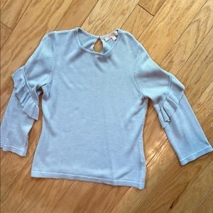 Light blue cashmere sweater with a diagonal ruffle on the arm.